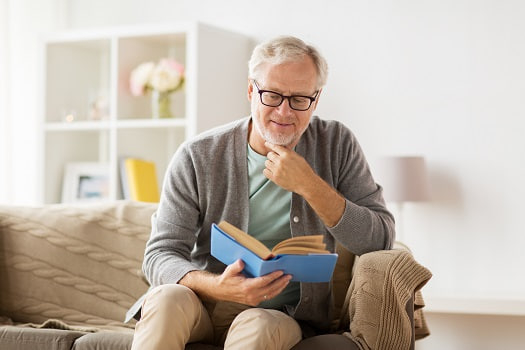 رجل مسن يقرأ كتابًا، معبرًا عن مرحلة الشيخوخة والنضج
