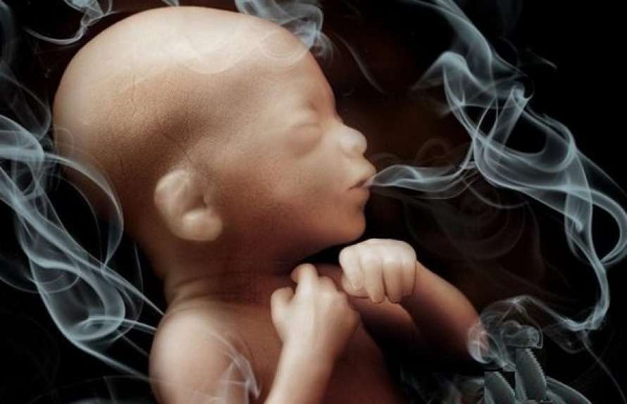 على خلفية سوداء يظهر جنين يلفه دخان التدخين 