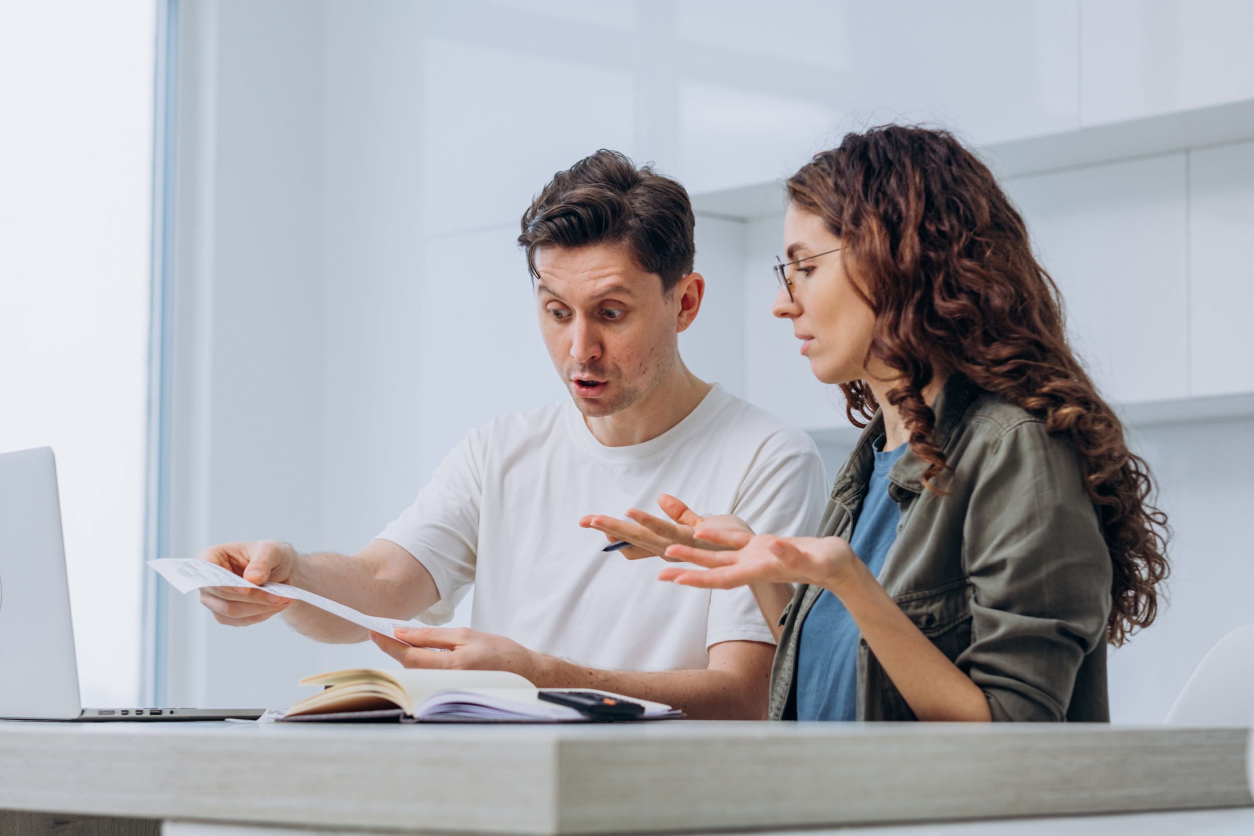 زوج يمسك ورقة حساب و يتناقش بحده مع زوجته التي تحمل قلم و ترفع يديها استهجانا 