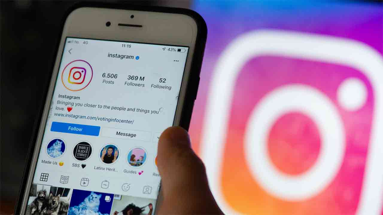 على خلفية يظهر فيها شعار انستغرام تظهر يد ممسكة بهاتف ذكي تظهر على شاشته صفحة انستغرام 