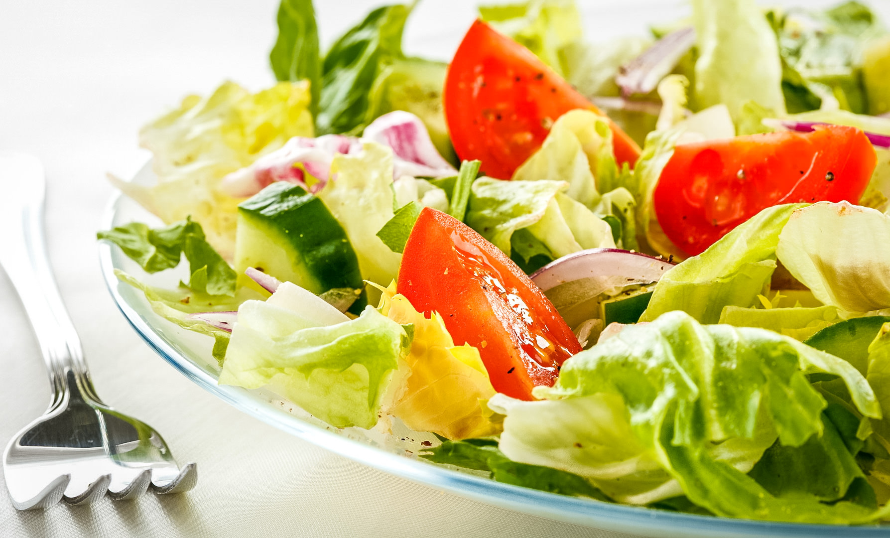 طبق يحوي سلطة من الخس والبندورة والخيار وبجانب الطبق شوكة 