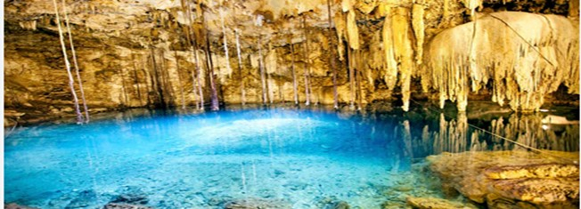 مغارة صخورها متدليه وفي وسط المغارة بركة زرقاء صافية 