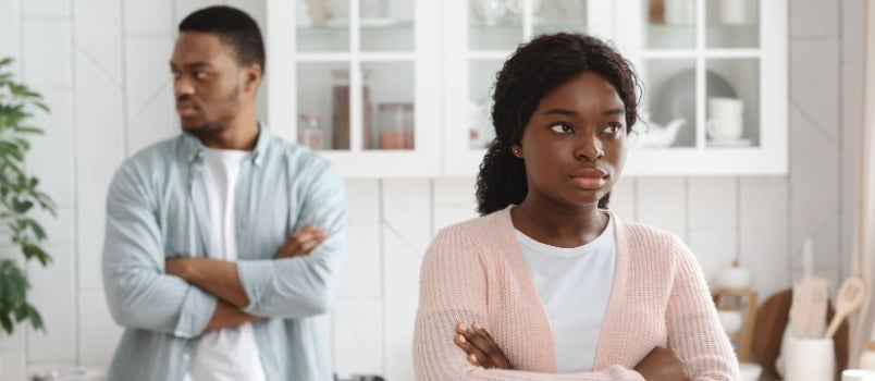 زوج وزوجة يديران ظهرهما لبعضهما بعد خلاف وهم يعقدون ذرايعيهما الى صدرهما بتوتر 