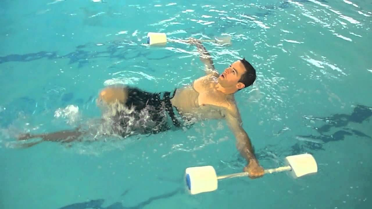 شاب يسبح في بركة السباحة و هو يحمل بذراعيه اثقال 