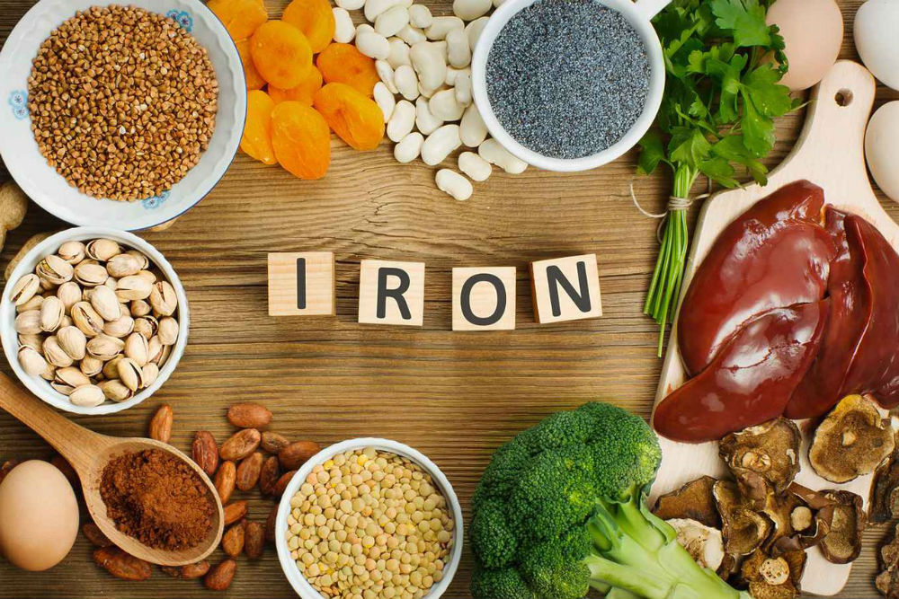 فيتامين الحديد مكعبات عليها احرف تشكل كلمة IRON وحولها الكبده و الفستق الحلبي و البيض و العدس و غيرها