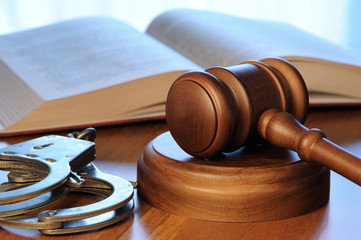 كتاب القانون و بجانبه مطرقة القاضي و اصفاد لاعتقال المجرمين 