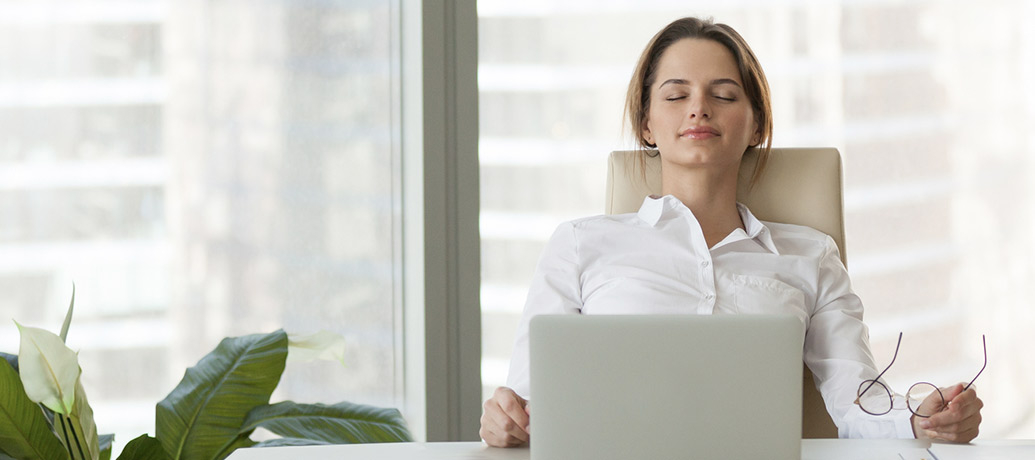 سيدة جالسة في مكتبها تسند راسها للكرسي ممسكة بنظاراتها الطبية مغلقة عينها تنشد الراحة 