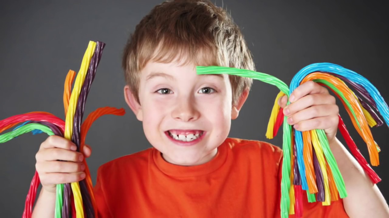 طفل مبتهج يمسك بيديه قطع الحلوى الملونة 