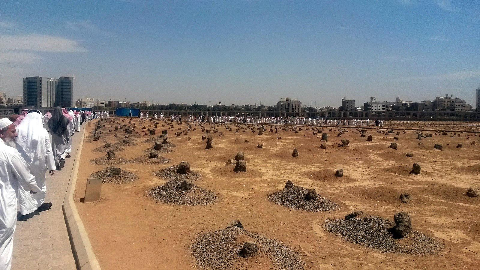 مقبرة البقيع و يظهر قبور محددة بحجارة و على طرفها طريق يسير فيه المالناس 