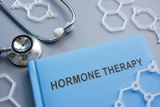 العلاج الهرموني للعقم على طاولة رمادية يظهر سجل يظهر عليه عبارة HORMONE THERAPY وبجانبها سماعة طبيب