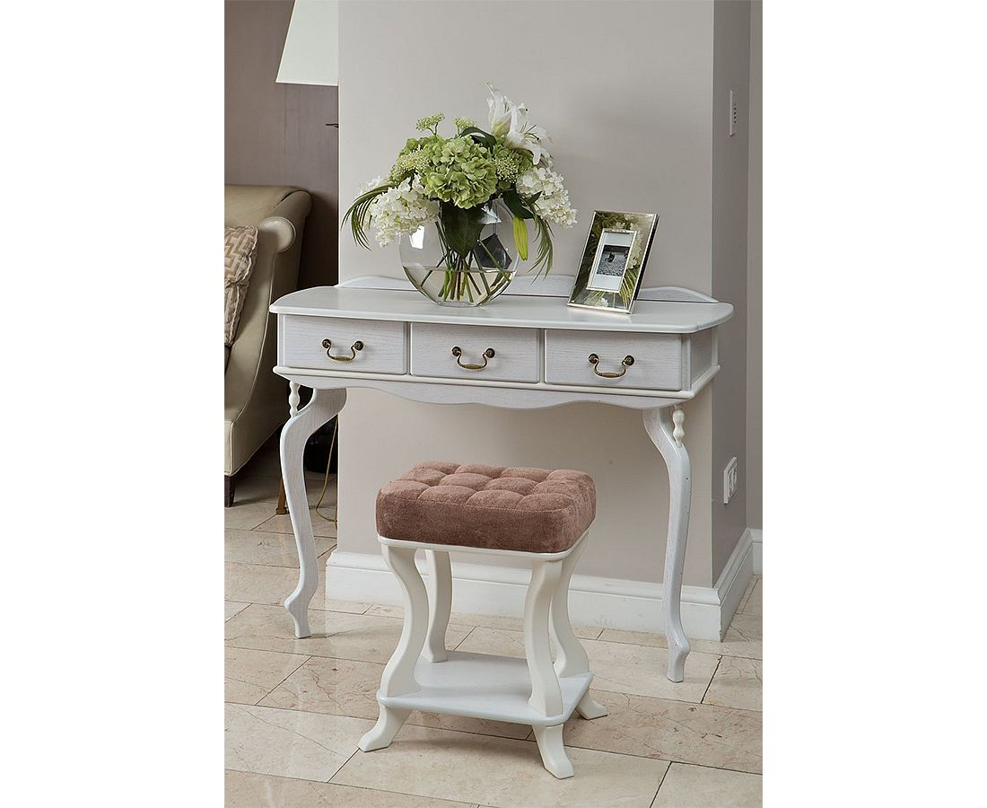 كونسول ابيض انيق ضيق عند مدخل المنزل مزين ب تابلو صور مع فازه بيضوية و ازهار ونباتات خضراء و امامه كرسي ابيض بدون مسند مصنوع من القطيفة الزهرية 