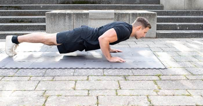 رجل يرتدي تيشيرت وشورت اسود في منطقة مرصوفة بالحجارة و هو يمارس تمرين الضغط 