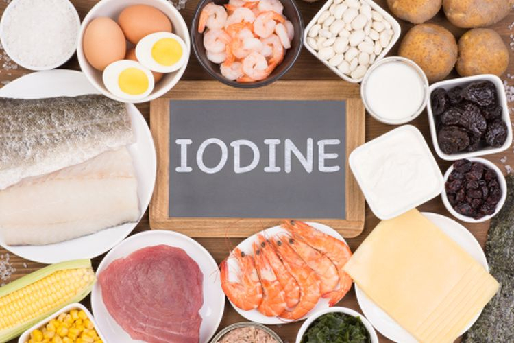 اليود لوح خشبي مكتوب عليه IODINE وحوله اغذية غنية باليود مثل السمك و اللحم الاحمر و البيض و الذرة و الفاصولياء و غيرها