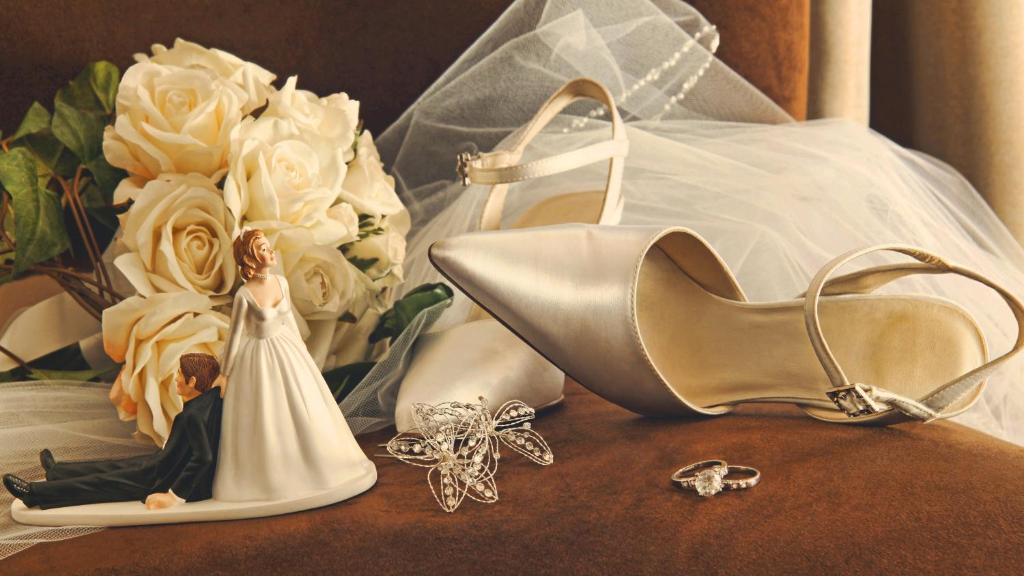 يظهر مجسم عريس و عروس بجانبهم بكلات شعر ذهبية للعروس و خواتم العروسين مع جزء من الطرحة وباقة ورد مخصصة للعروس 