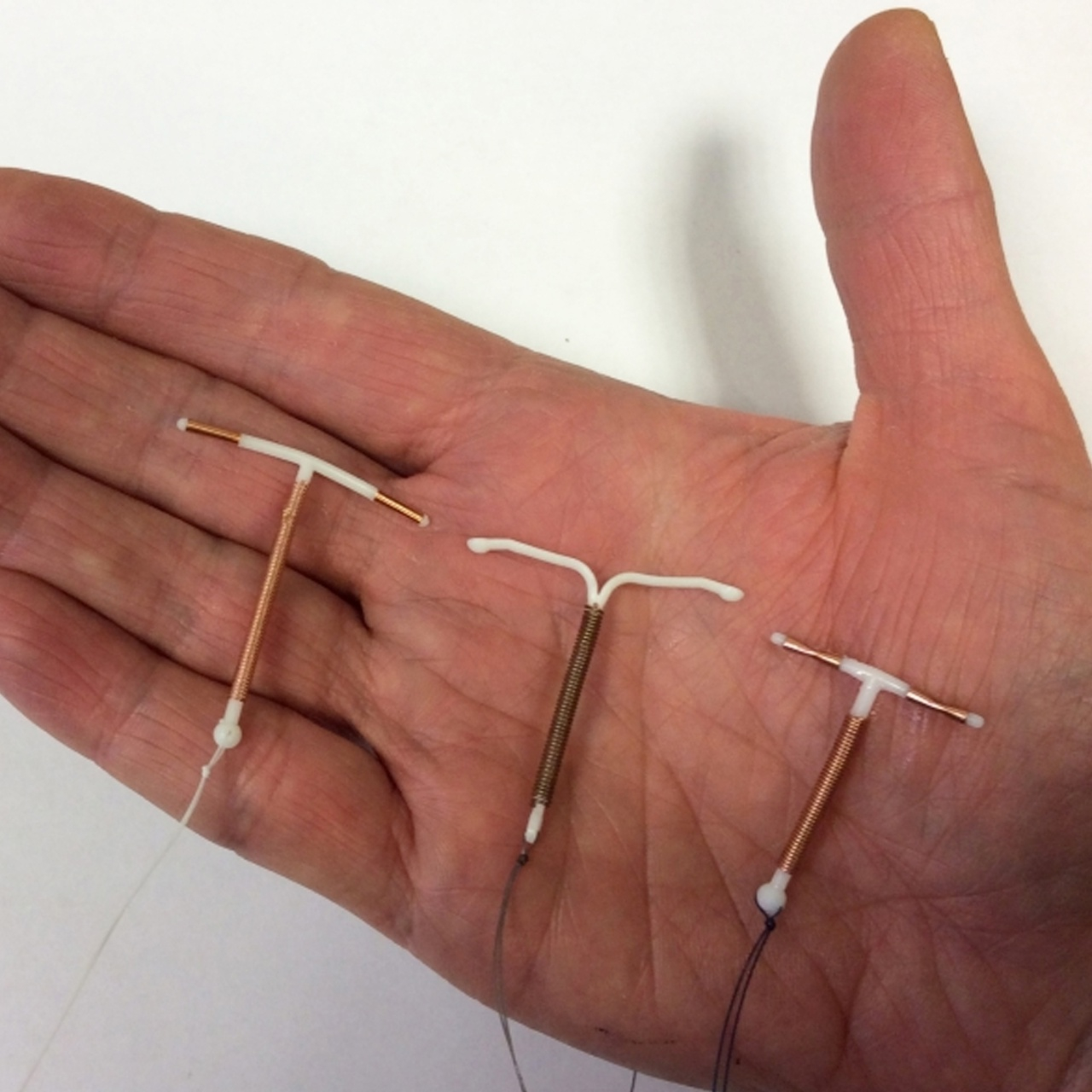 على خلفية بيضاء تظهر يد مفتوحة و عليها ثلاث انواع من لولب منع الحمل 