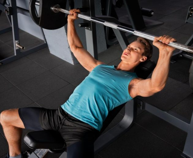 رجل يرتدي تيشيرت ازرق وشورت اسود وه يمارس تمارين البنس برس 