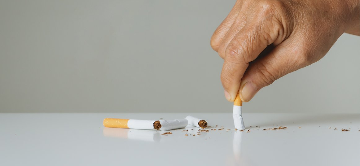 شخص يسحق سيجارة على طاولة و بجابنه سيكارة اخرى مكسورة 