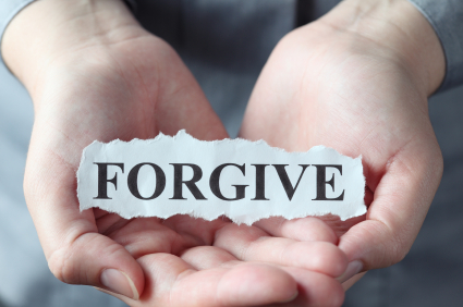 يدين تحملان ورقة مكتوب عليها كلمة FORGIVE