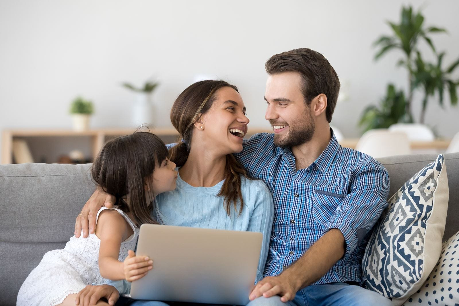 تعزيز العلاقات الزوجية زوجين سعيدين يتشاركان الاوقات مع طفلتهما وهما يضحكان وهم يستخدمون اللابتوب