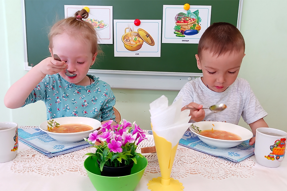 آداب الطعام عند الأطفال طفلين يجلسان الى مائدة الطعام و يلتزمان بقواعد تناول الطعام