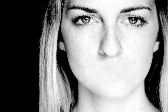 على خلفية سوداء وصورة بالابيض والاسود تظهر فتاه ليس لها فم 