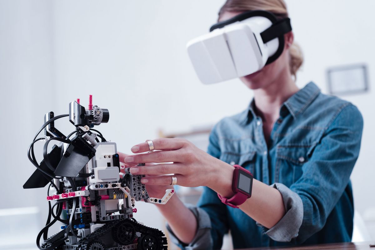 سيدة تضع نظارات افتراضية و تمد يديها لصيانة جهاز امامها 