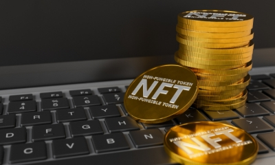 مجموعة من النقود الذهبية موضوعة على لوحة مفاتحي كميبوتر واحدى القطع النقدية مكتوب عليها NFT