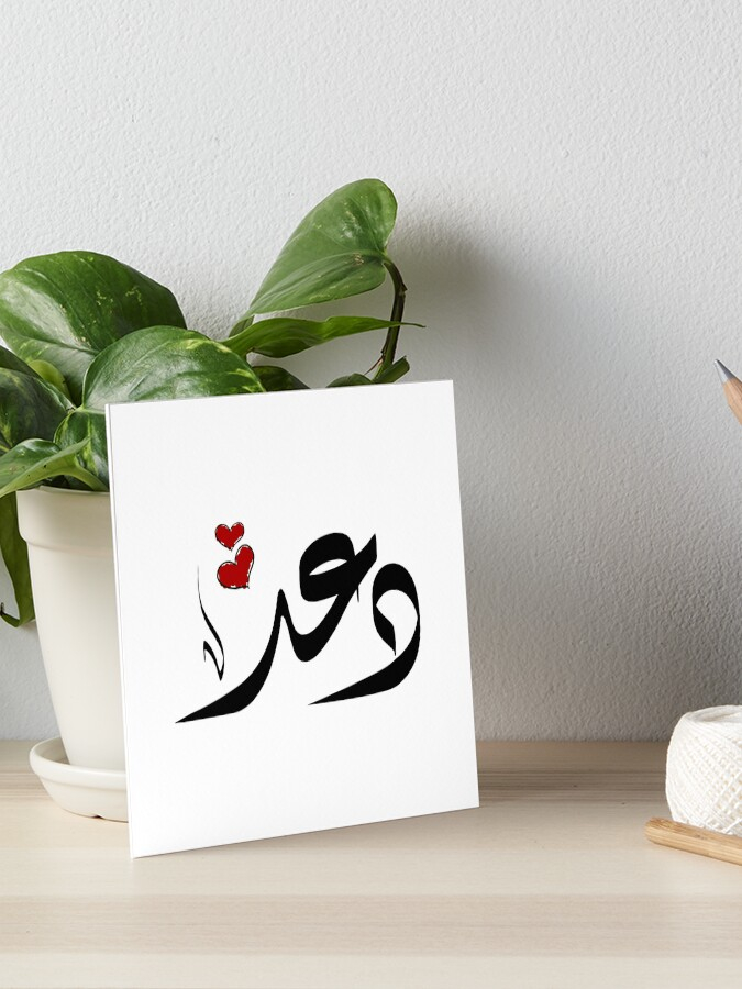 اسم دعد على طاولة بيضاء تظهر ورقة مستنده الى قصيص نبته خضراء و يظهر اسم دعد على الورق مكتوب باللون الاسود