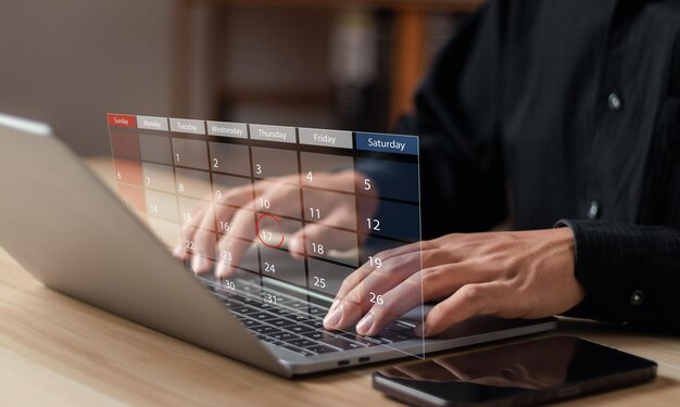 شخص ينقر على لوحة المفاتيح لجهاز لابتوب و تظهر بشكل افتراضي اجندة تذكير