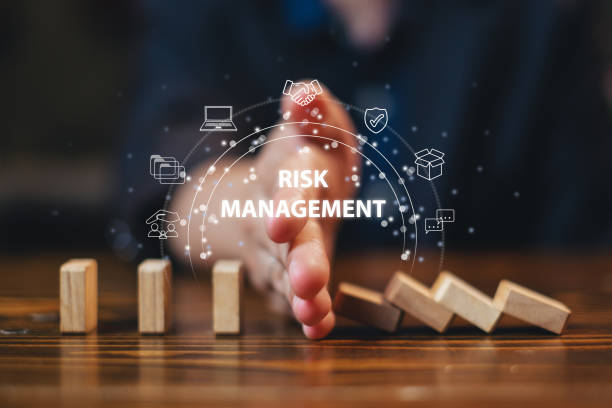 يد شخص تفصل بين مجموعة من المكعبات الخشبية المتساقطة و تمنعها من الوصول الى المكعبات التي تقف بتوازن وتظهر عباةر Risk Management