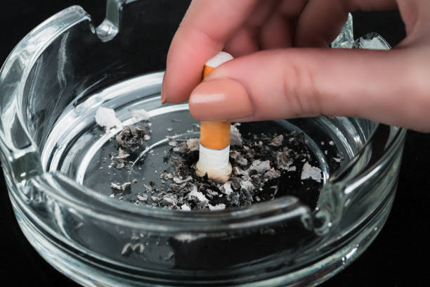 يد تطفيء سيجارة في صحن شفاف