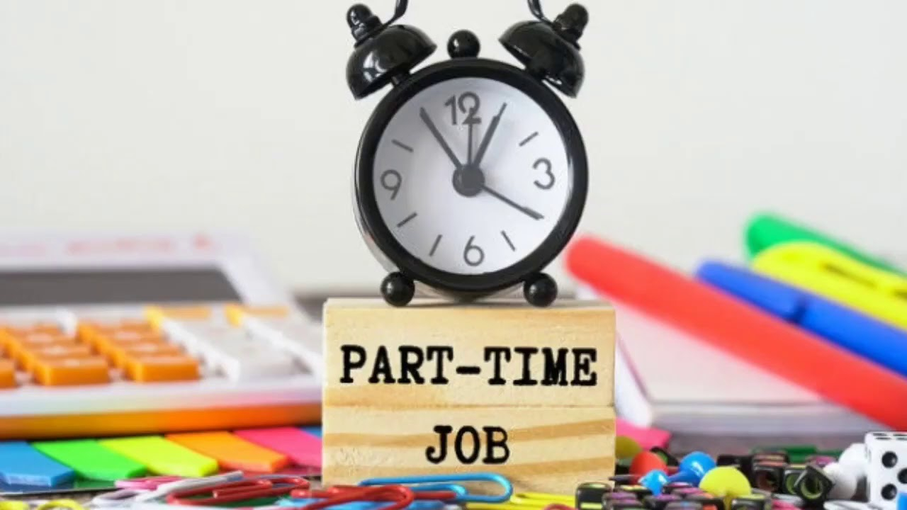 على خلفية تحوي لوحة مفاتيح و اقلام ملونة يظهر مكعب مكتوب عليه عبارة PART TIME JOB  وفوقه ساعة منبه لونها اسود