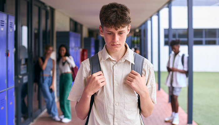 شب مراهق يمشي في اروقة المدرسة مطأطأ رأسه حزينا 