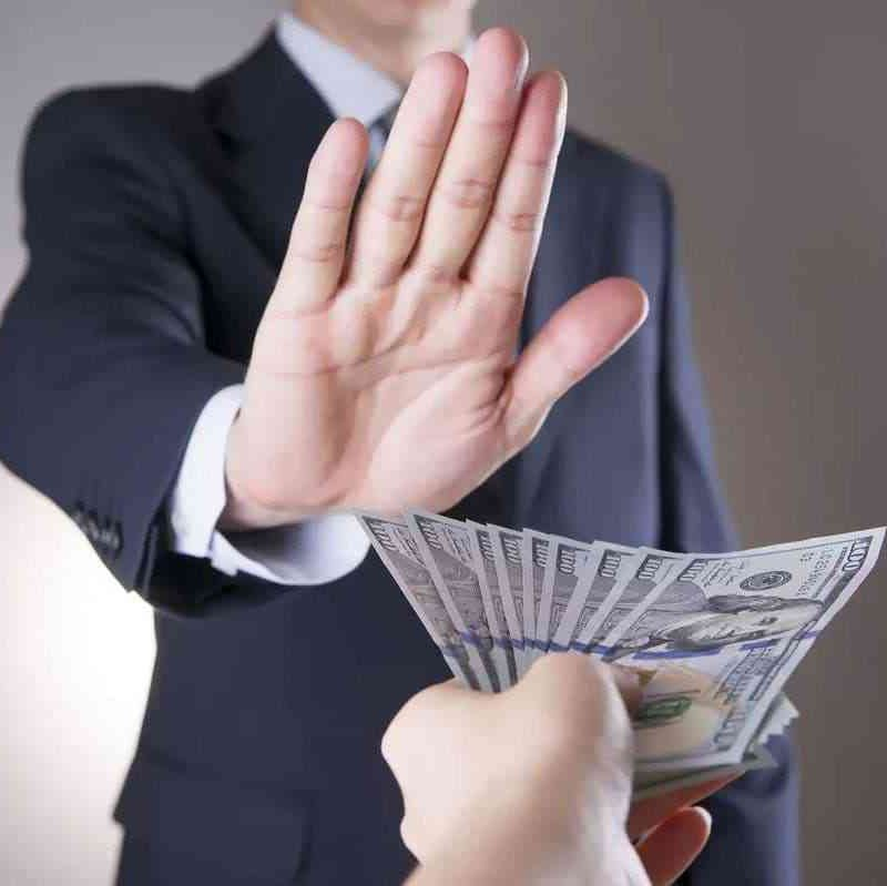 رجل يرفع يده رافضا القبول برشوة يقدمها شخص يمسك بالعديد من الاوراق النقدية 