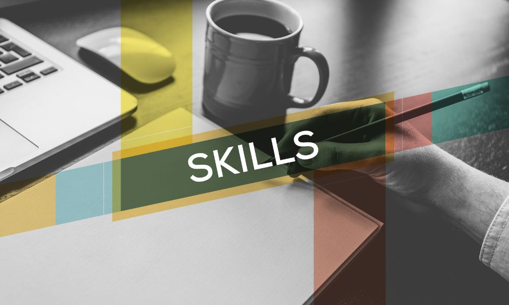 يد شخص تمسك قلم و امامه دفتر و يظهر طرف جهاز لابتوب 