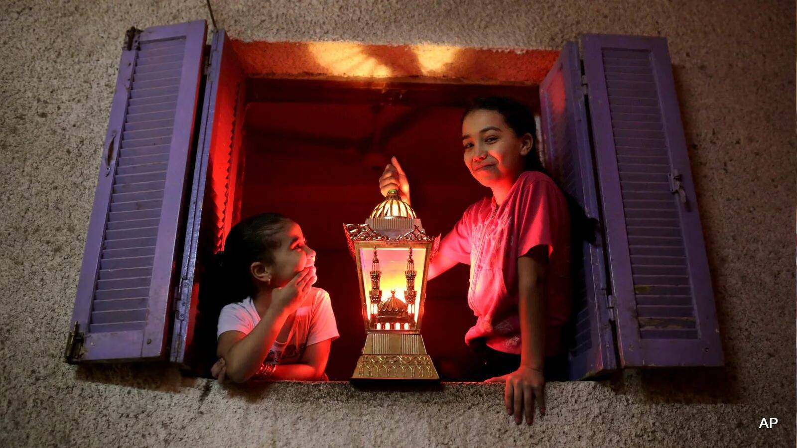 فتاة تطل من النافذة وتحمل فانوس رمضان