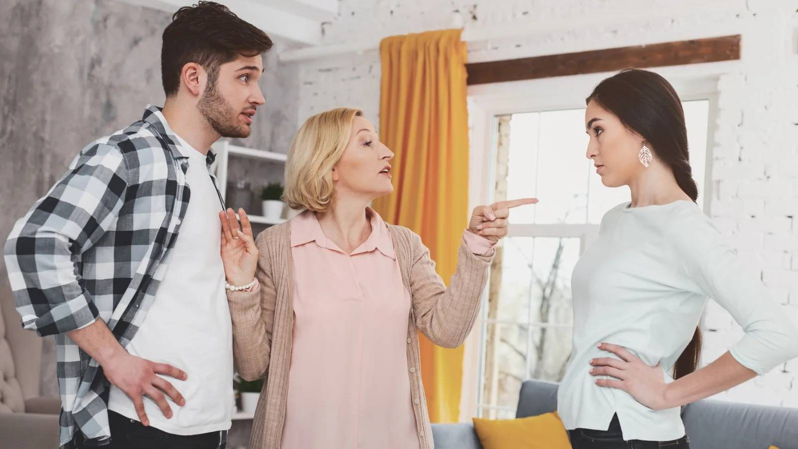 الام توجه اصبع الاتهام نحو الزوجة ويقف الزوج بجانب الام واضعا يديه على خصره