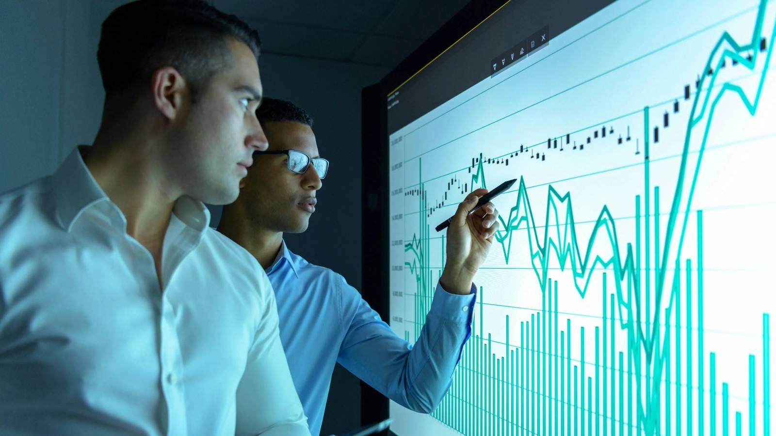 موظفين يحللان الوضع المالي على شاشة كبيرة