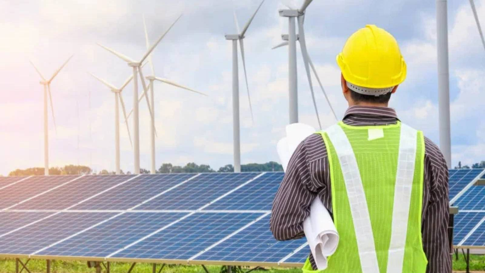 مهندس يحمل تحت ابطه مجموعة من الخرائط والروسات ويشرف على حقل من الالواح الشمسية للطاقة المتجدده