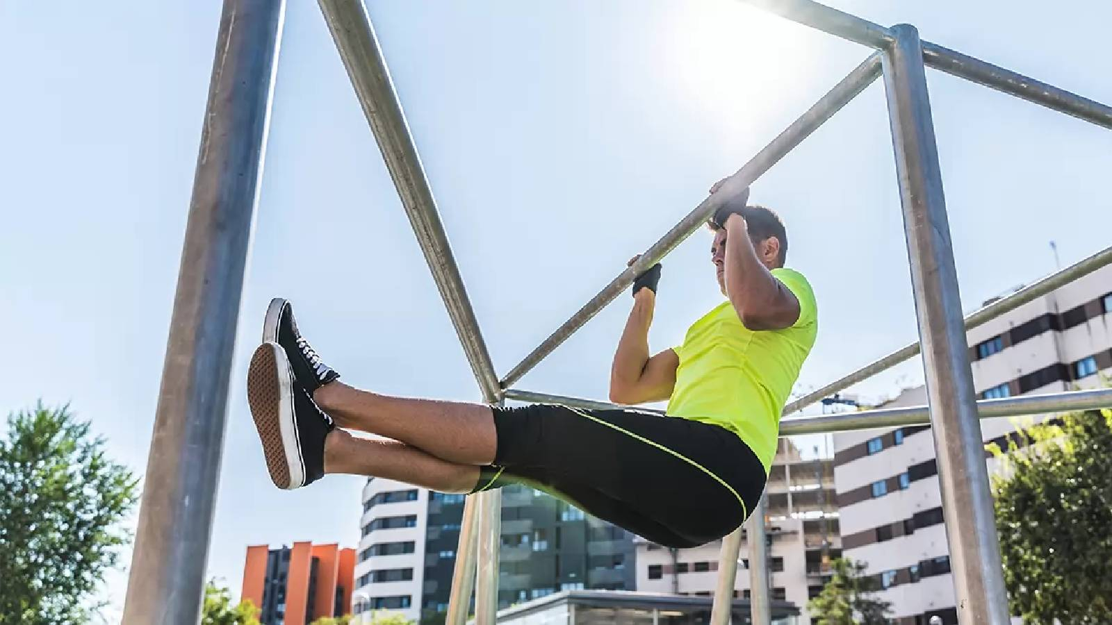 رجل في الهواء الطلق برتدي تيشيرت اصفر ويمارس تمارين السحب للاعلى 