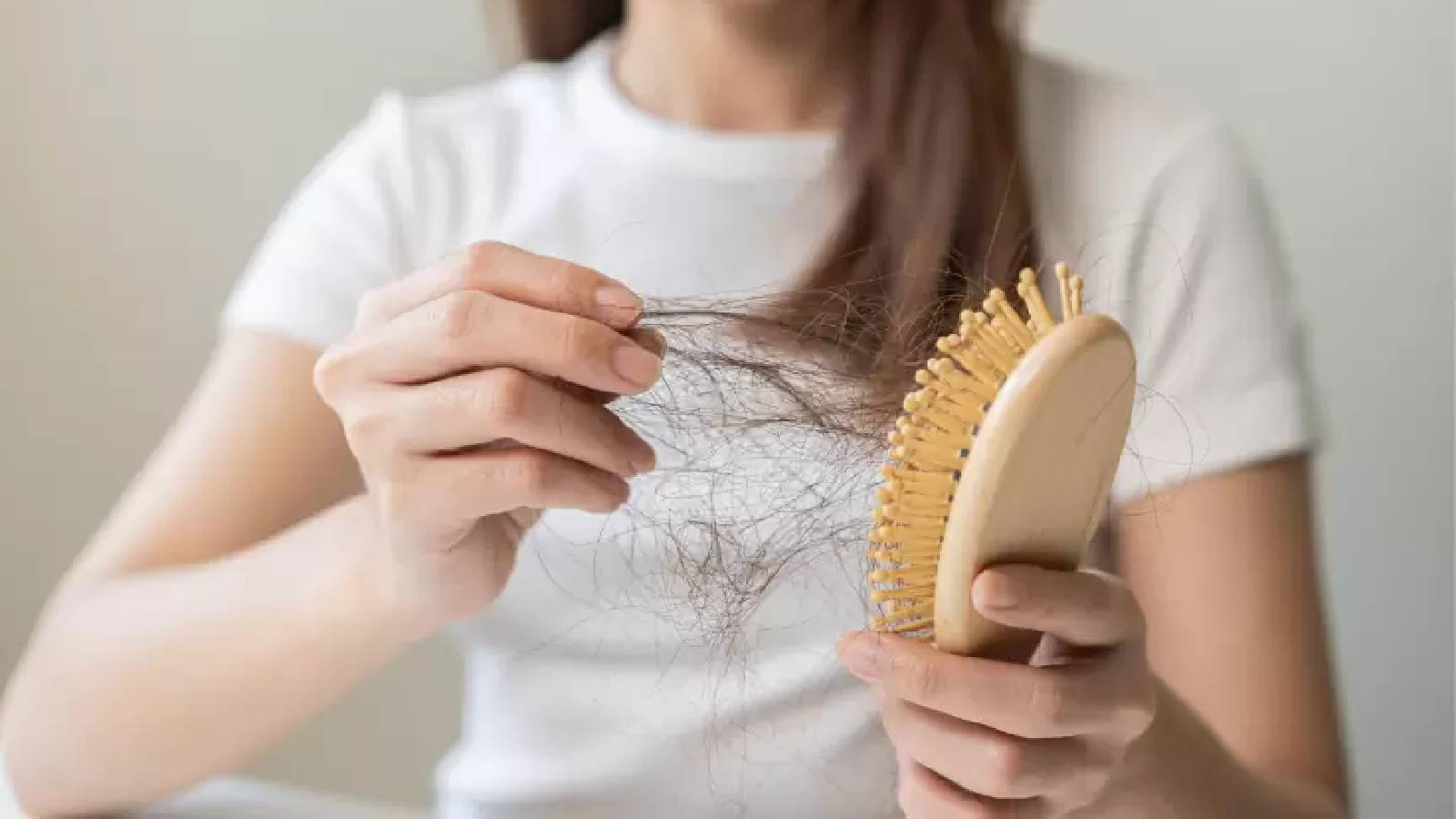 سيدة تمسك بيدها فرشاة شعرها و تخرج منها خصلات الشعر المتساقطة 