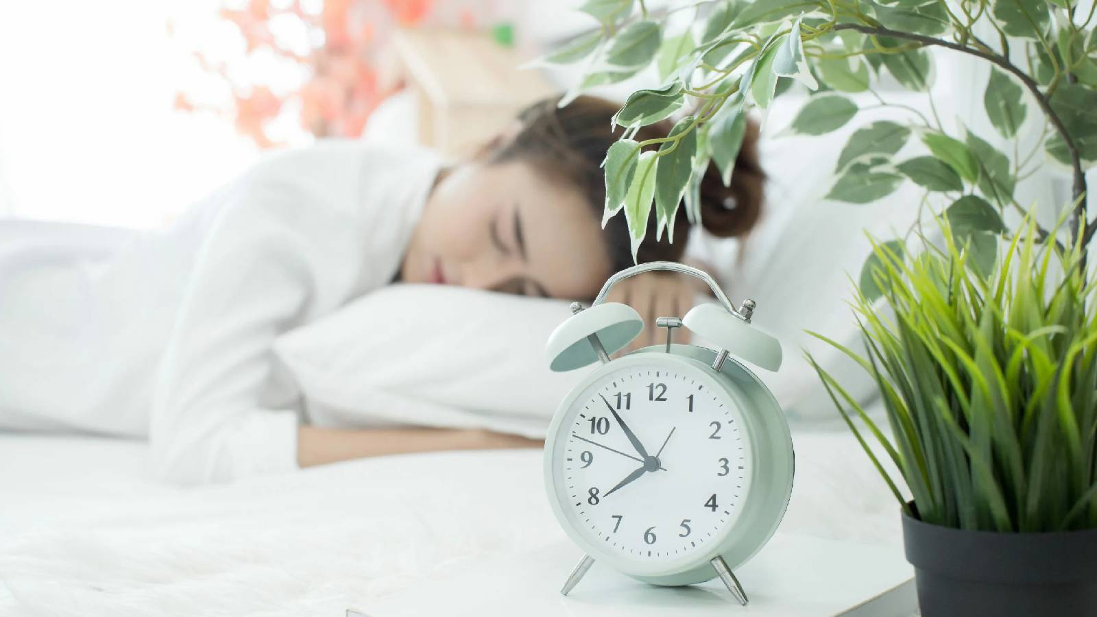 سيدة تنام و بجانبها ساعة منبه بيضاء