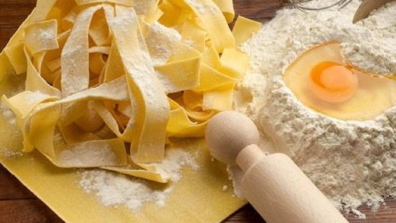 شرائح الباستا بجانبها دقيق و عليه بيضة ويوجد شوبك لفرد العجينة