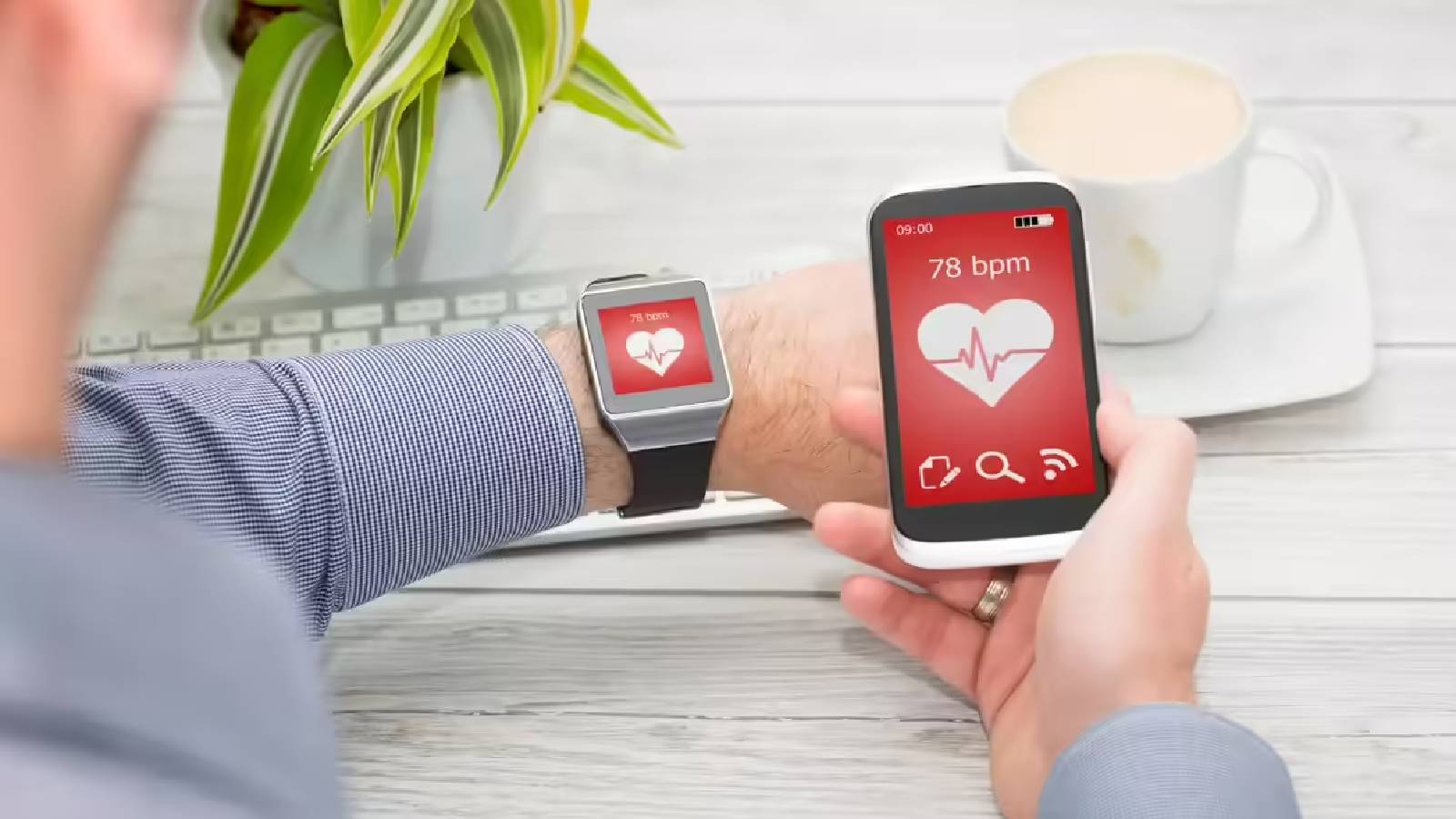 شخص يحمل بيده اليمين جهاز هاتف ذكي وتظهر على شاشته تخطيط دقات القلب و في يده السيار ساعة ذكية تظهر على شاشته تطبيق متابعة المؤشرات الحيوية 