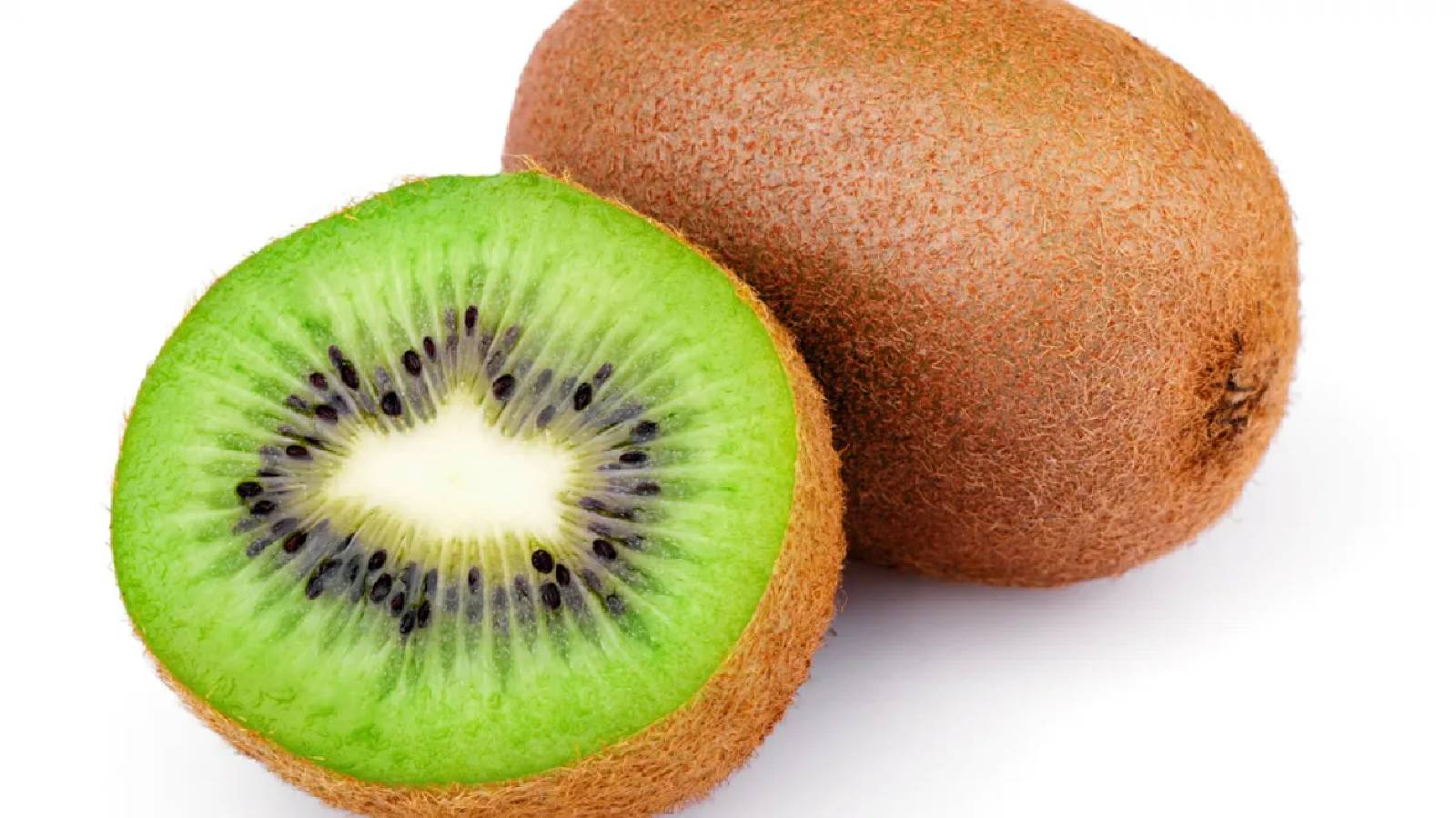 حبة من فواكه الكيوي و بجانبها قطعة كيوي مقسومة تظهر داخلها لوث الثمرة الخضراء و في الوسط بقعة بيضاء و بجانبها خطوط شعاعية تحوي بذور سوداء صغيرة 