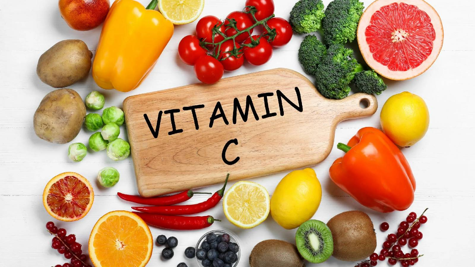 لوح تقطيع من الخشب مكتوب عليه VITAMIN C و حوله الكثير من الاغذية العنية بفيتامين سي مثل البرتقال و الفليفلة و الكيوي و البندورة وغيرها 
